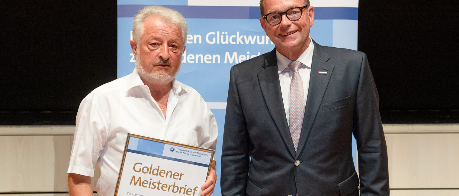 Kammerpräsident Klaus Hofmann überreicht Gas- Wasserinstallateurmeister Bernhard Schlag auf der Goldene Meisterfeier in Wiesloch 2022 seinen Goldenen Meisterbrief