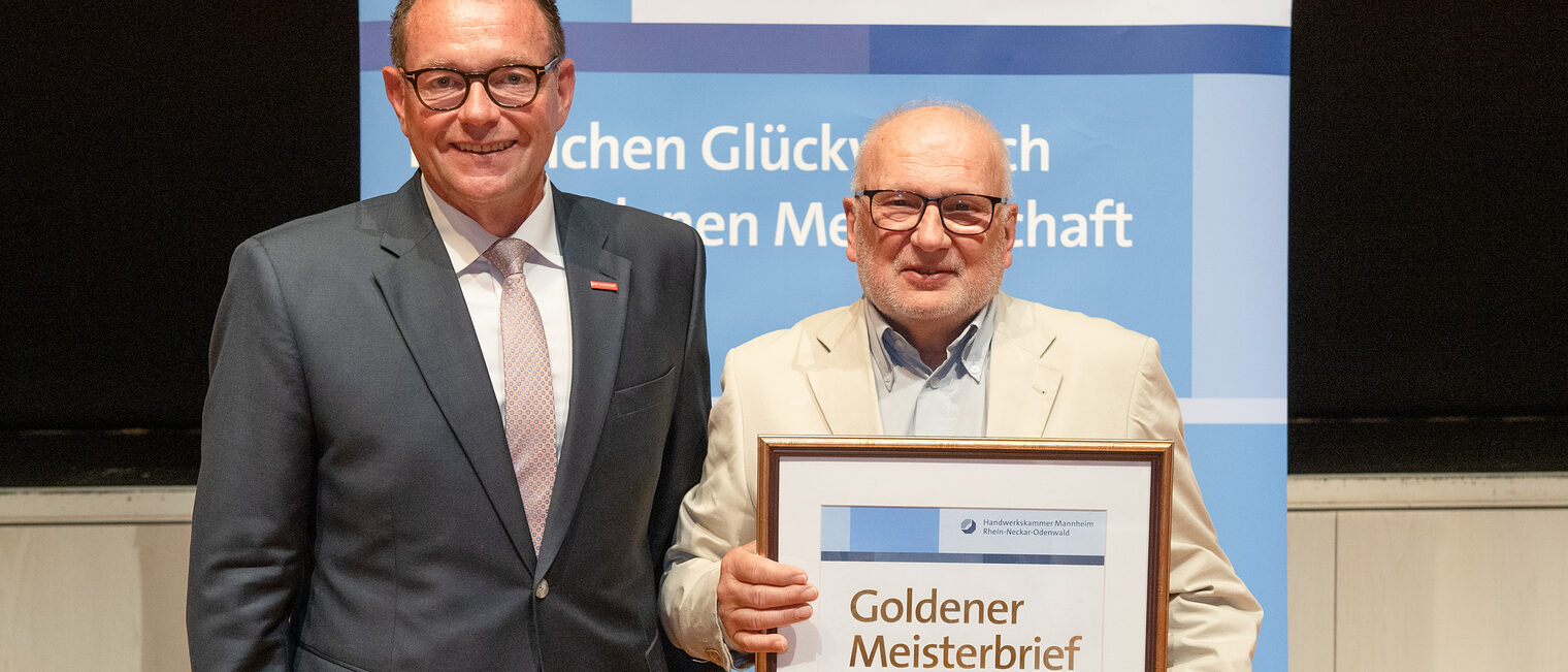Kammerpräsident Klaus Hofmann überreicht Werzeugmechanikermeister Hans Georg Schleich auf der Goldene Meisterfeier in Wiesloch 2022 seinen Goldenen Meisterbrief