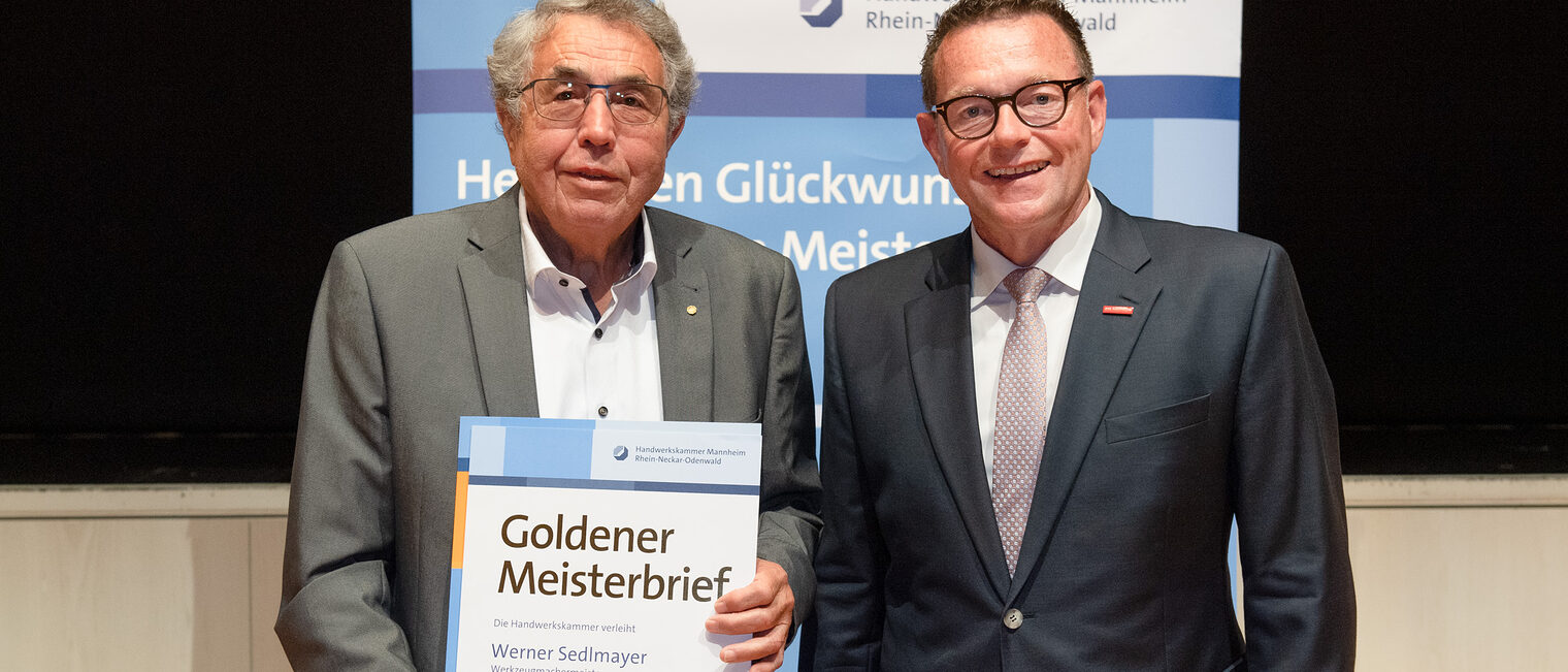 Kammerpräsident Klaus Hofmann überreicht Werkzeugmechanikermeister Werner Sedlmayer auf der Goldene Meisterfeier in Wiesloch 2022 seinen Goldenen Meisterbrief
