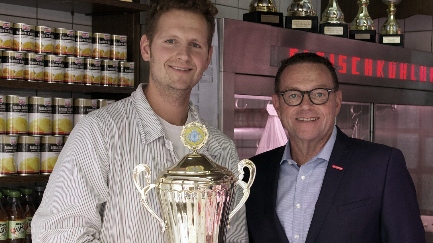 links: Philipp Burkhardt mit Pokal in den Händen und rechts Präsident Hofmann