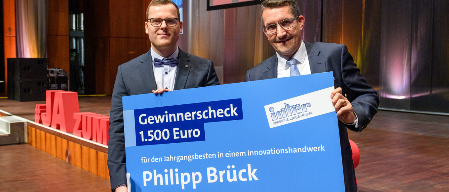 Alexander Verwiebe (rechts). Philipp Br&uuml;ck links h&auml;lt den Scheck in den H&auml;nden. 
