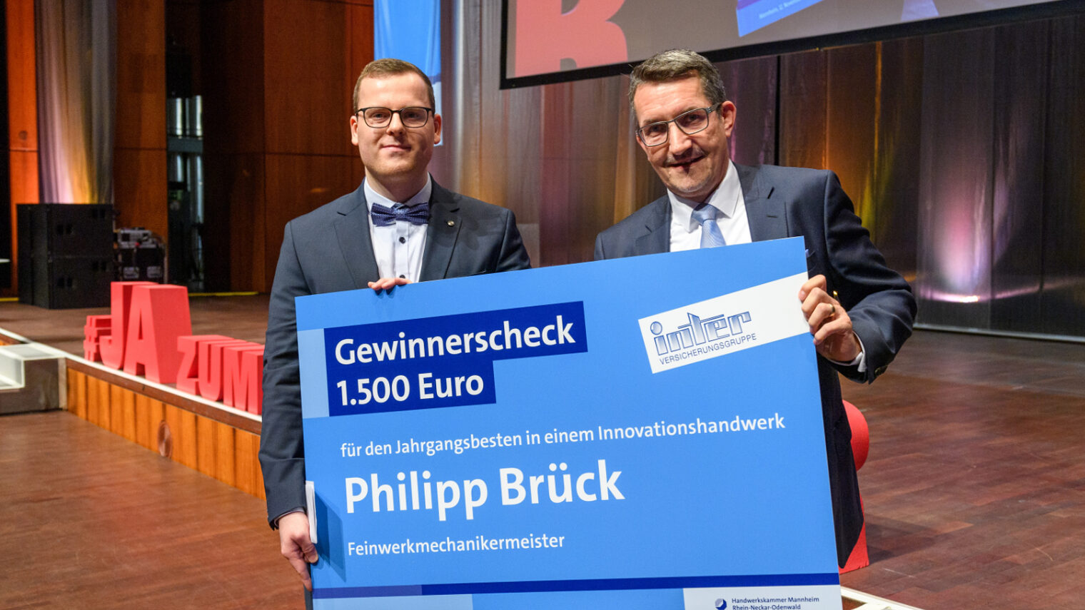 Alexander Verwiebe (rechts). Philipp Brück links hält den Scheck in den Händen. 