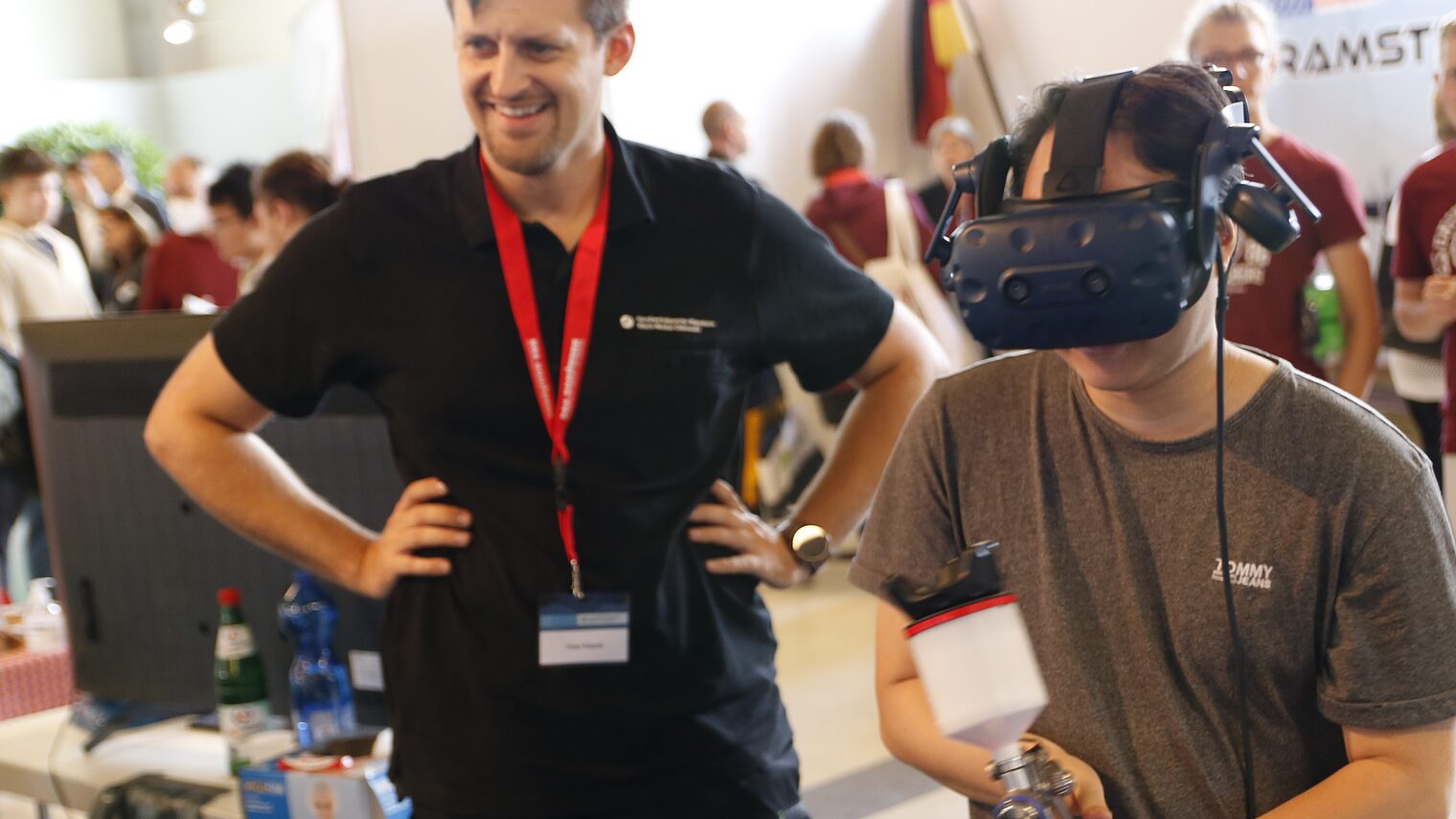 Ausbilder Timo Potsch zeigt interessiertem Schüler den Umgang mit der Farbspritzpistole als virtuelles Erlebnis mit der VR-Brille