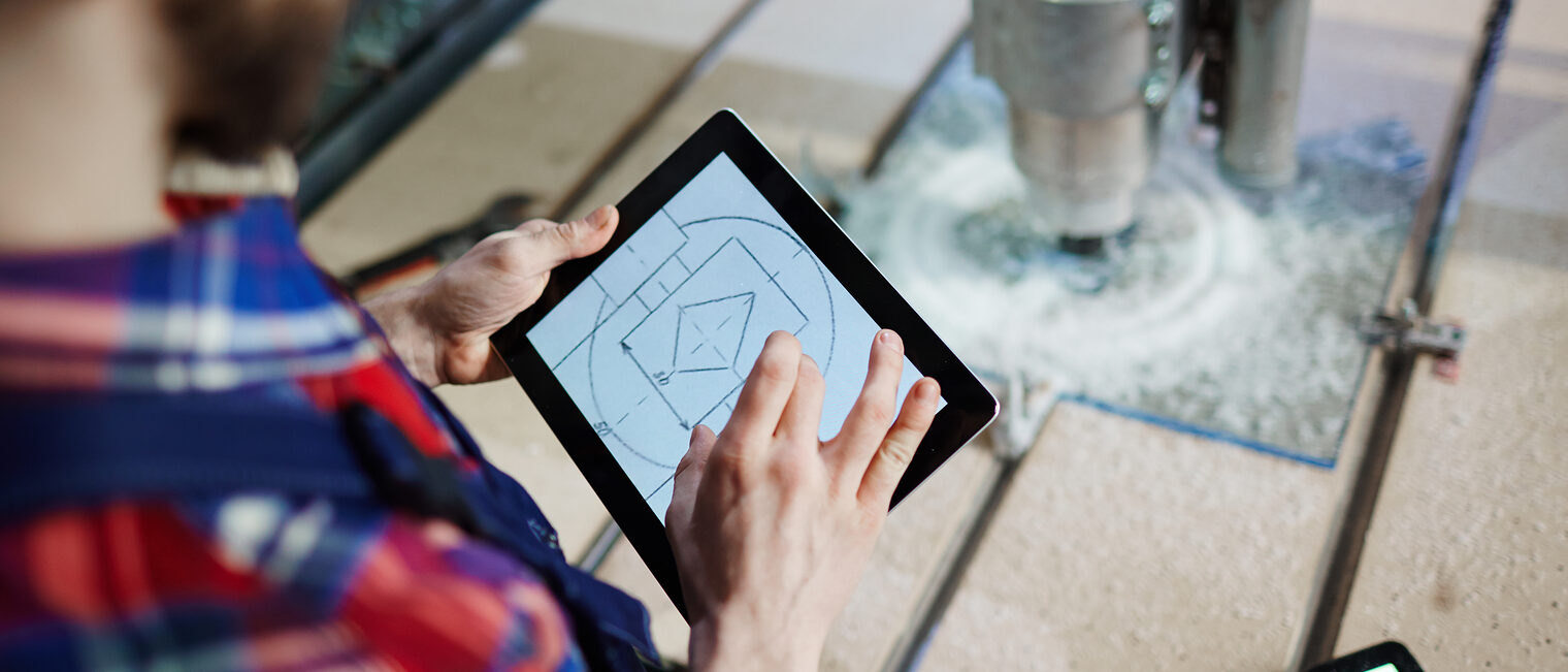 Handwerker an einer Fräsmaschiene mit einem Tablet in der Hand
