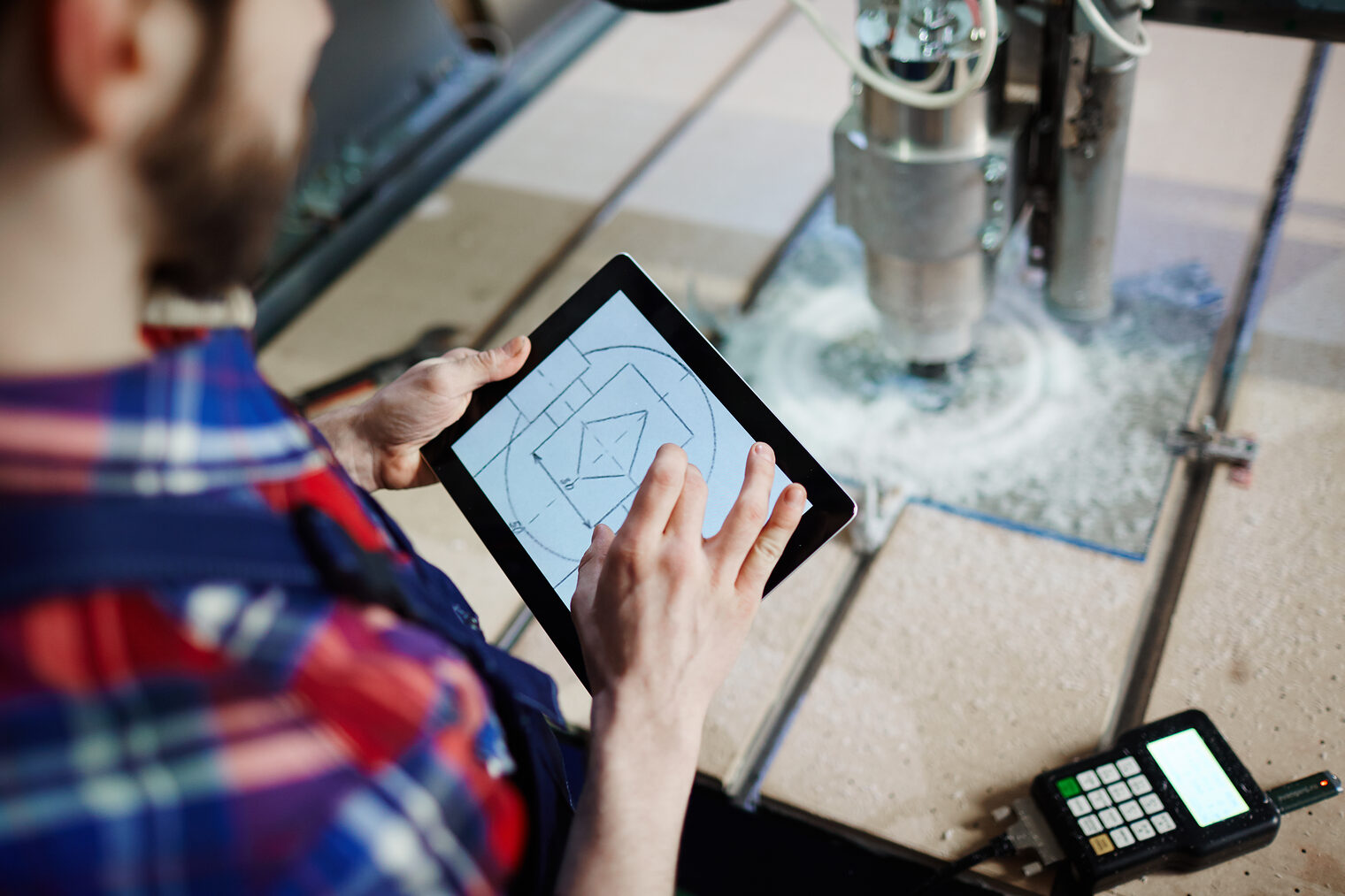 Handwerker an einer Fräsmaschiene mit einem Tablet in der Hand