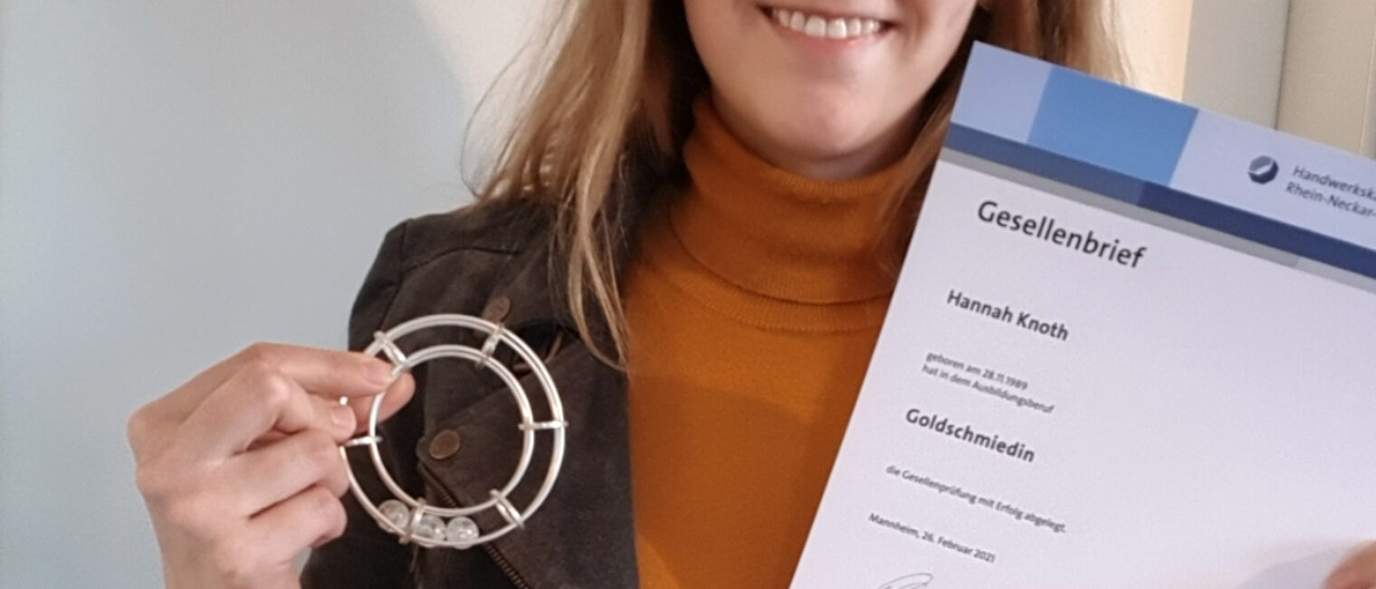 Goldschmiedin Hannah Knoth hält ihr Gesellenstück in der Hand. Dies ist ein silber geschmiedeter Armreif. 