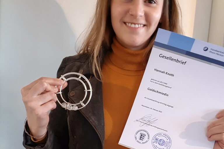 Goldschmiedin Hannah Knoth hält ihr Gesellenstück in der Hand. Dies ist ein silber geschmiedeter Armreif. 