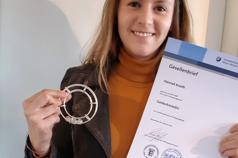 Goldschmiedin Hannah Knoth hält ihr Gesellenstück in der Hand. Dies ist ein silber geschmiedeter Armreif. 