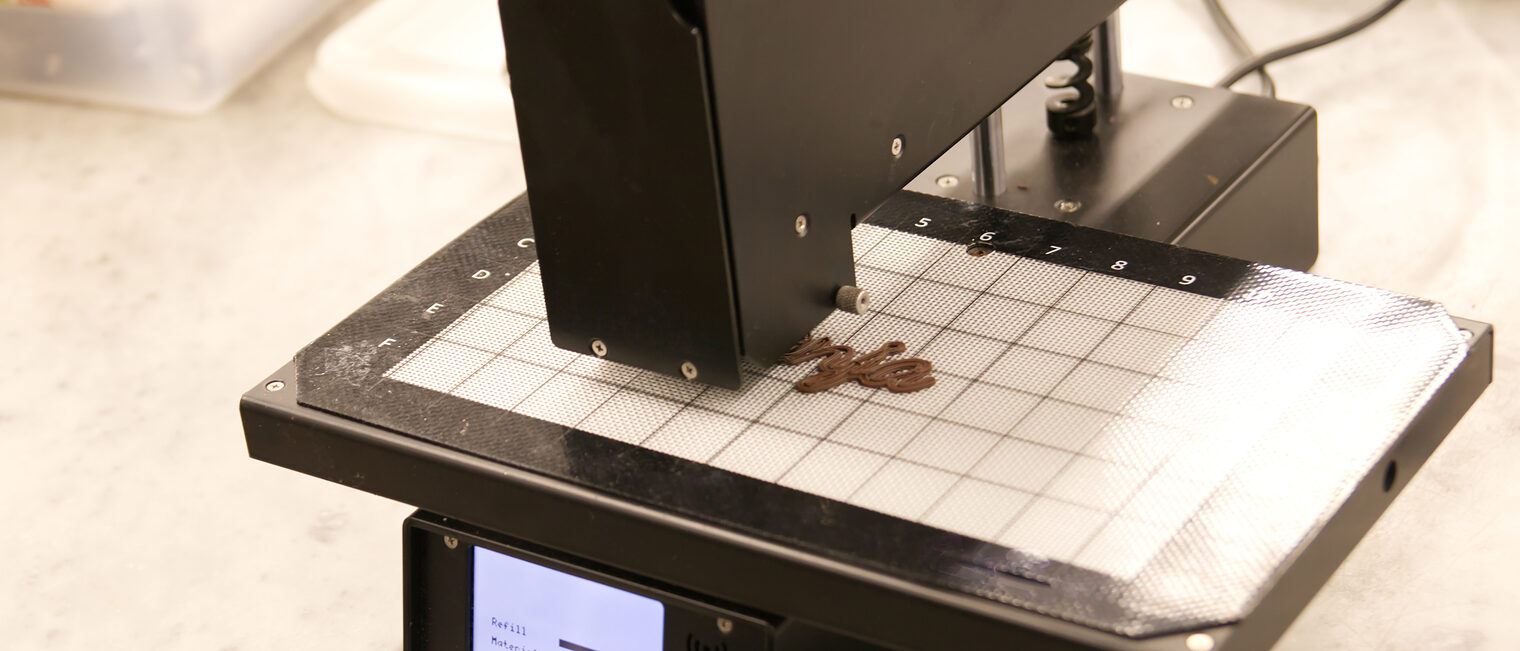 3D Food Printer, der eine Schriftzug aus Schokolade druckt