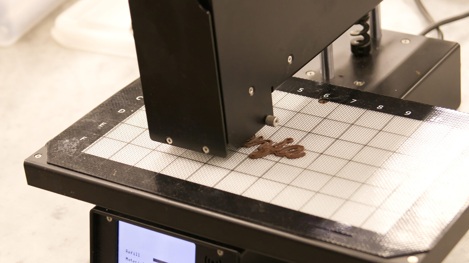 3D Food Printer, der eine Schriftzug aus Schokolade druckt