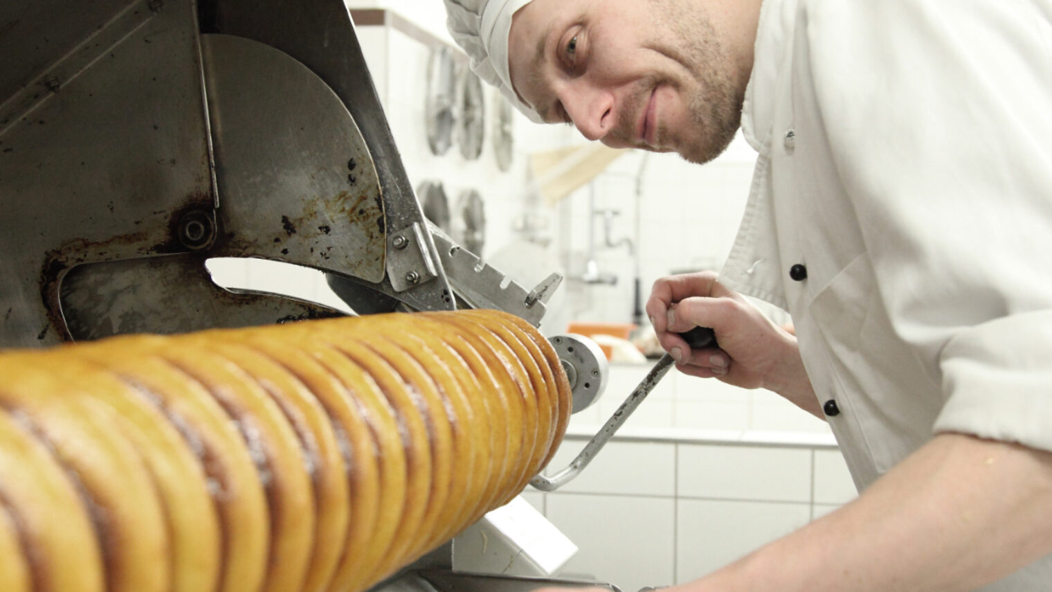 Konditor der mit seinem Baumkuchen beschäftigt ist