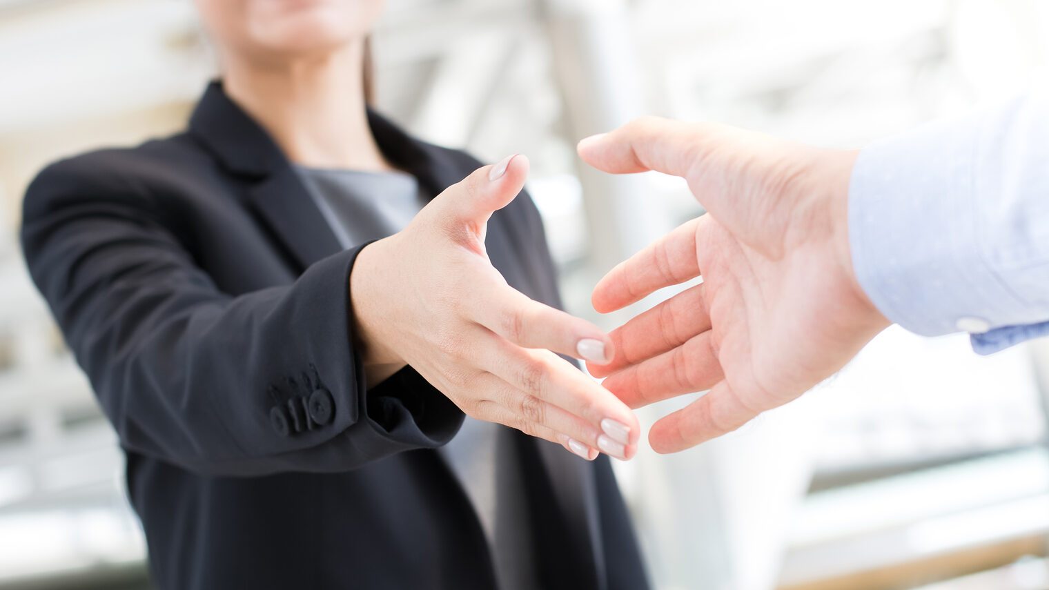 Junge lächelnde Frau reicht ihre Hand zum Gruß