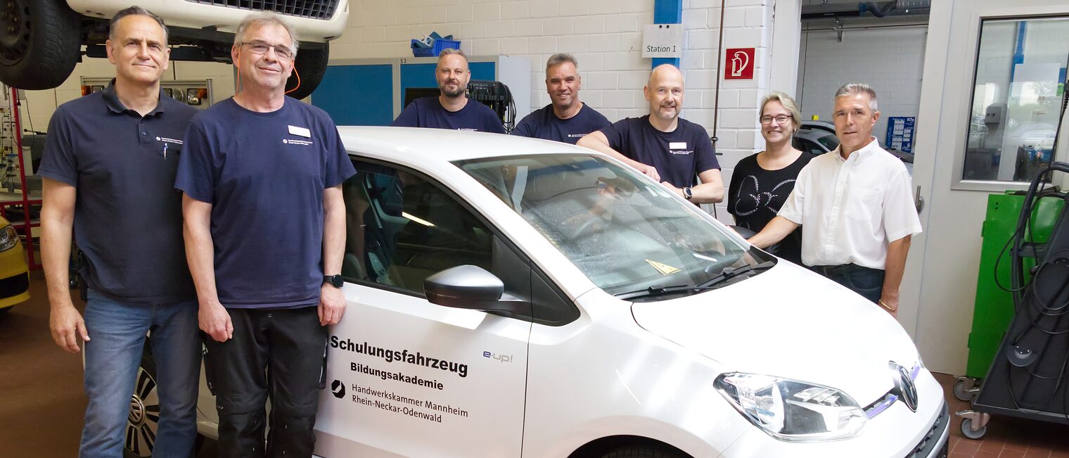 7 Leute freuen sich über das neue Schulungsfahrzeug für Elektromobilität in der Bildungsakademie Mannheim 