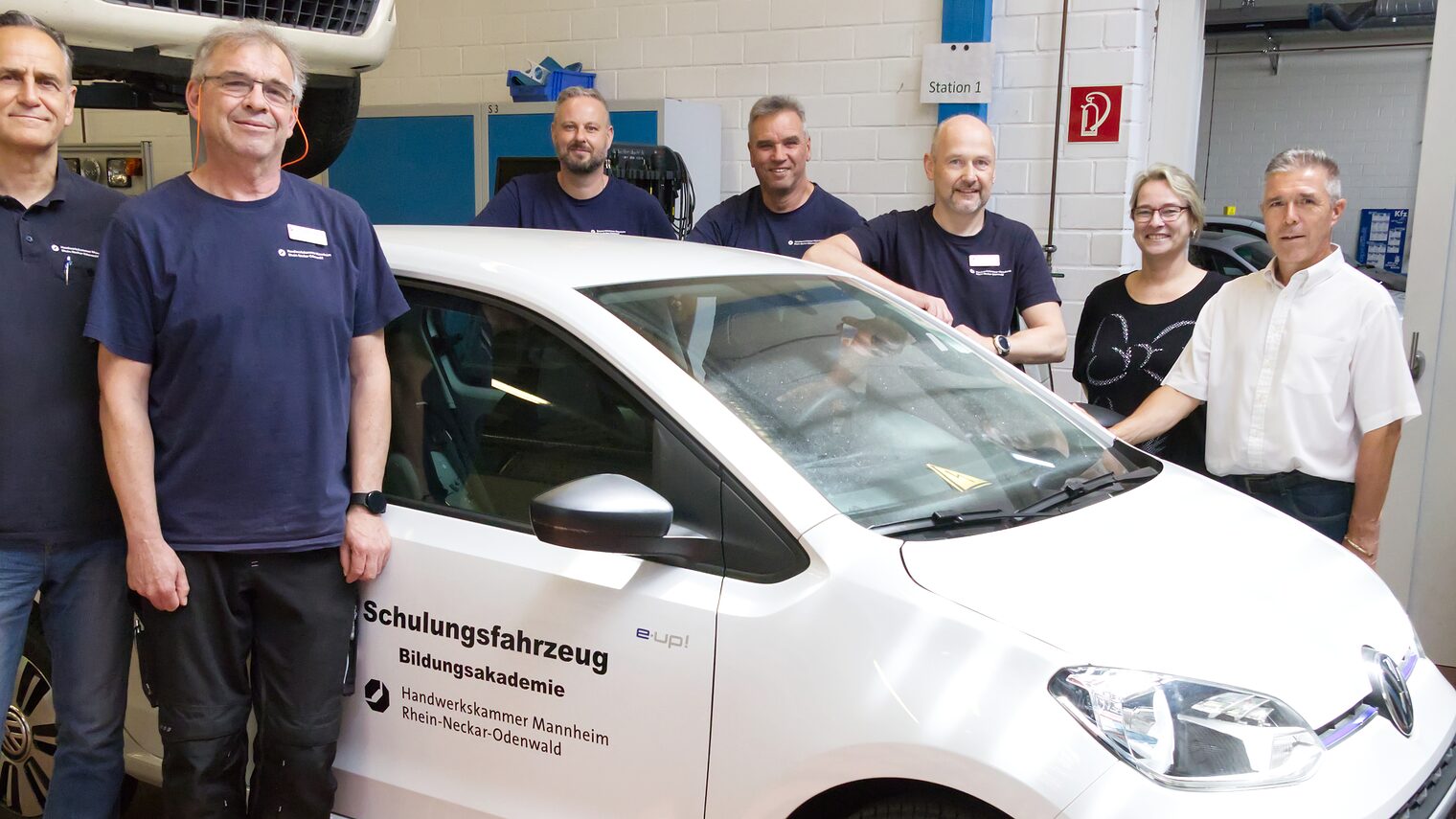 7 Leute freuen sich über das neue Schulungsfahrzeug für Elektromobilität in der Bildungsakademie Mannheim 