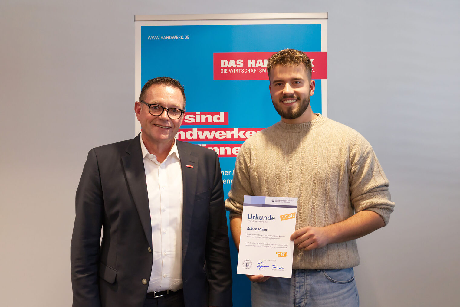 Schreiner Ruben Maier neben dem Präsidenten der Handwerkskammer, Klaus Hofmann, der ihm zum Gewinn beim Wettbewerb #zeigsallen gratuliert
