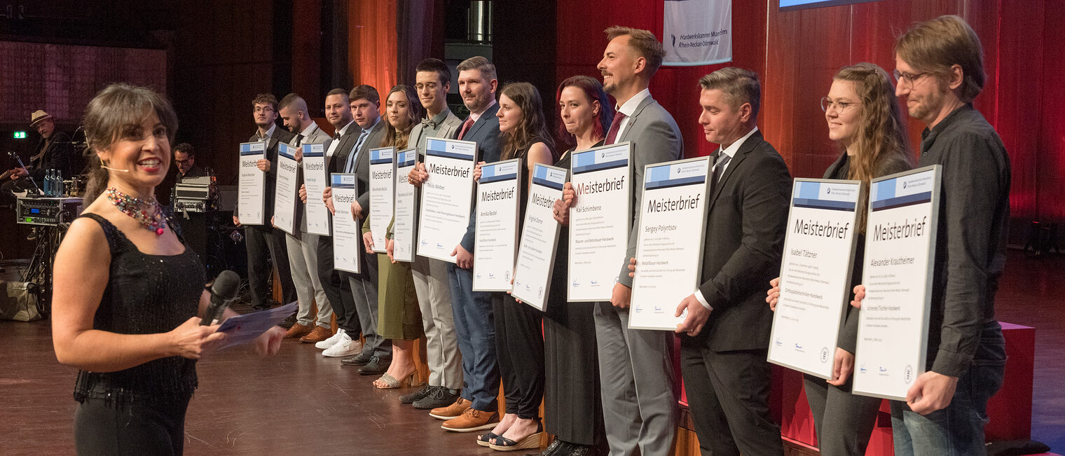 15 Gewerksbeste auf der Bühne der Meisterfeier 2023 mit Ihrem Meisterbriefen in der Hand. 
