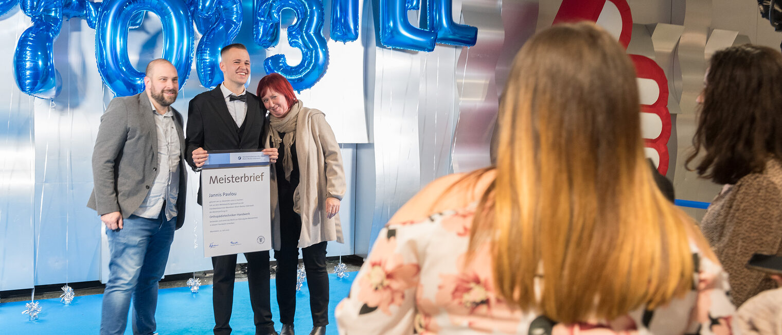 Orthopädietechnikermeister Jannis Pavlou wird mit seiner Familie auf der Meisterfeier im Foyer fotografiert.