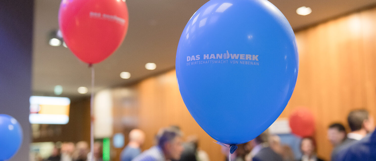 Zwei aufgeblasene Luftballons im Fokus und im Hintergrund sieht man verschwommen Gäste der Meisterfeier 2023.