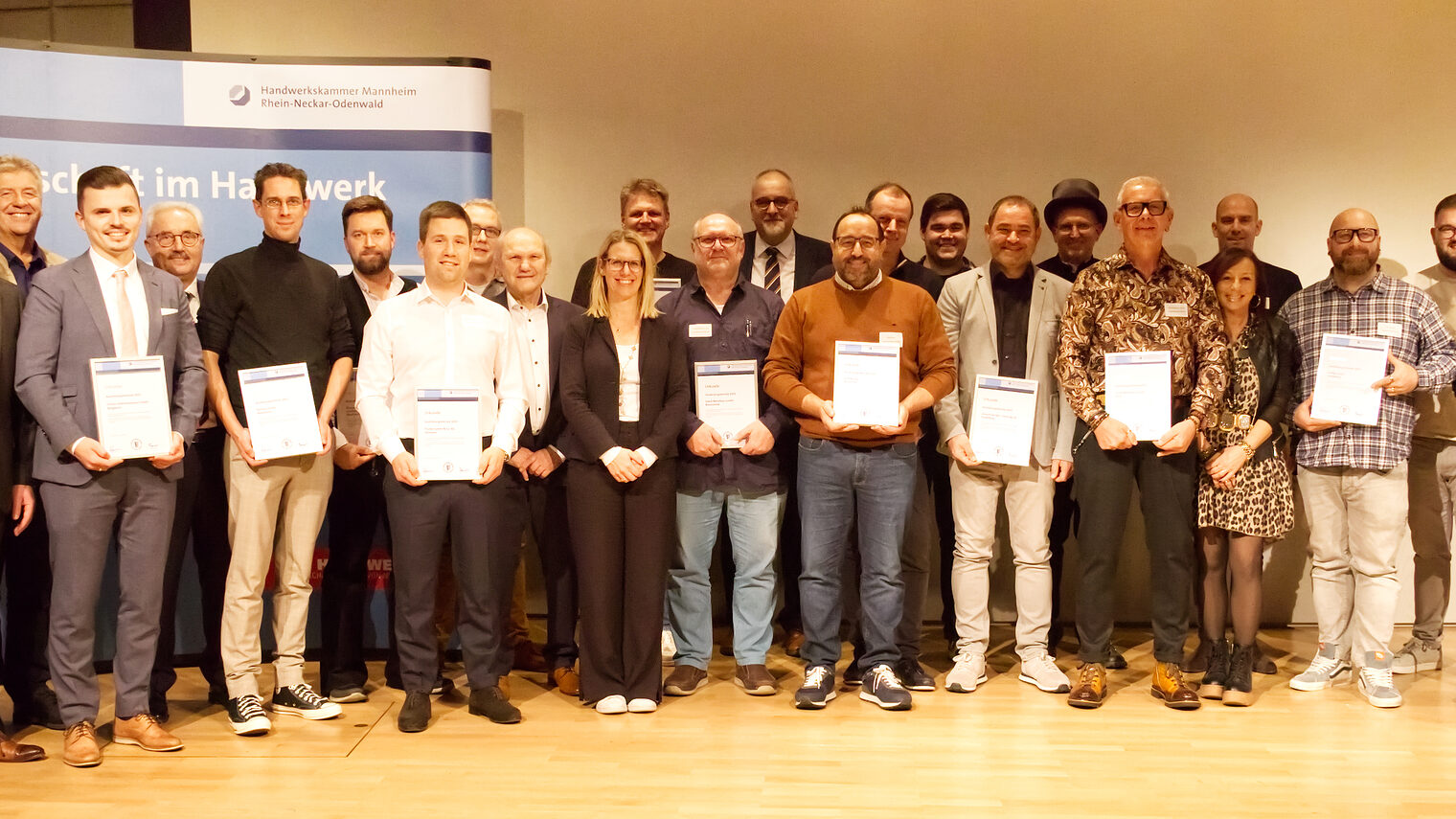 Gruppenfoto der Damen und Herren die ausgezeichnet wurden. Diese halten auch ihre Urkunde in die Kamera.