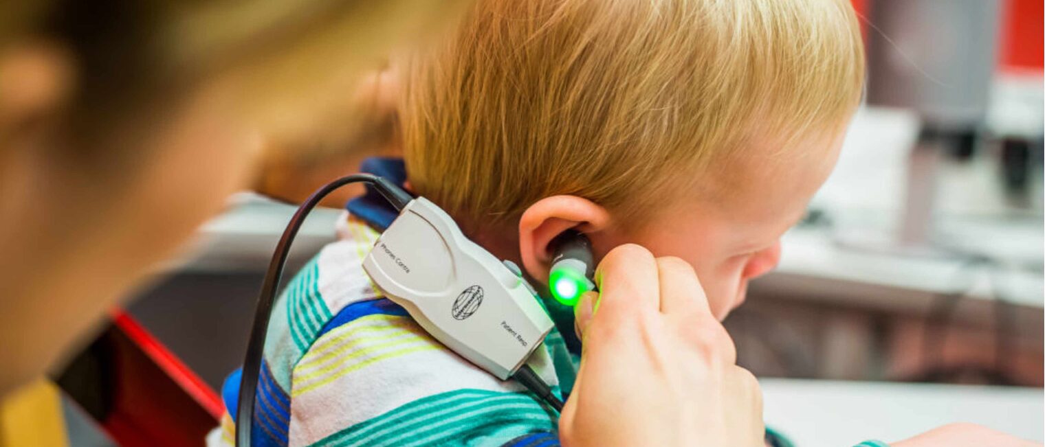 Bei einem Kind wird das Ohr durch einen Hörakustiker getestet. 
