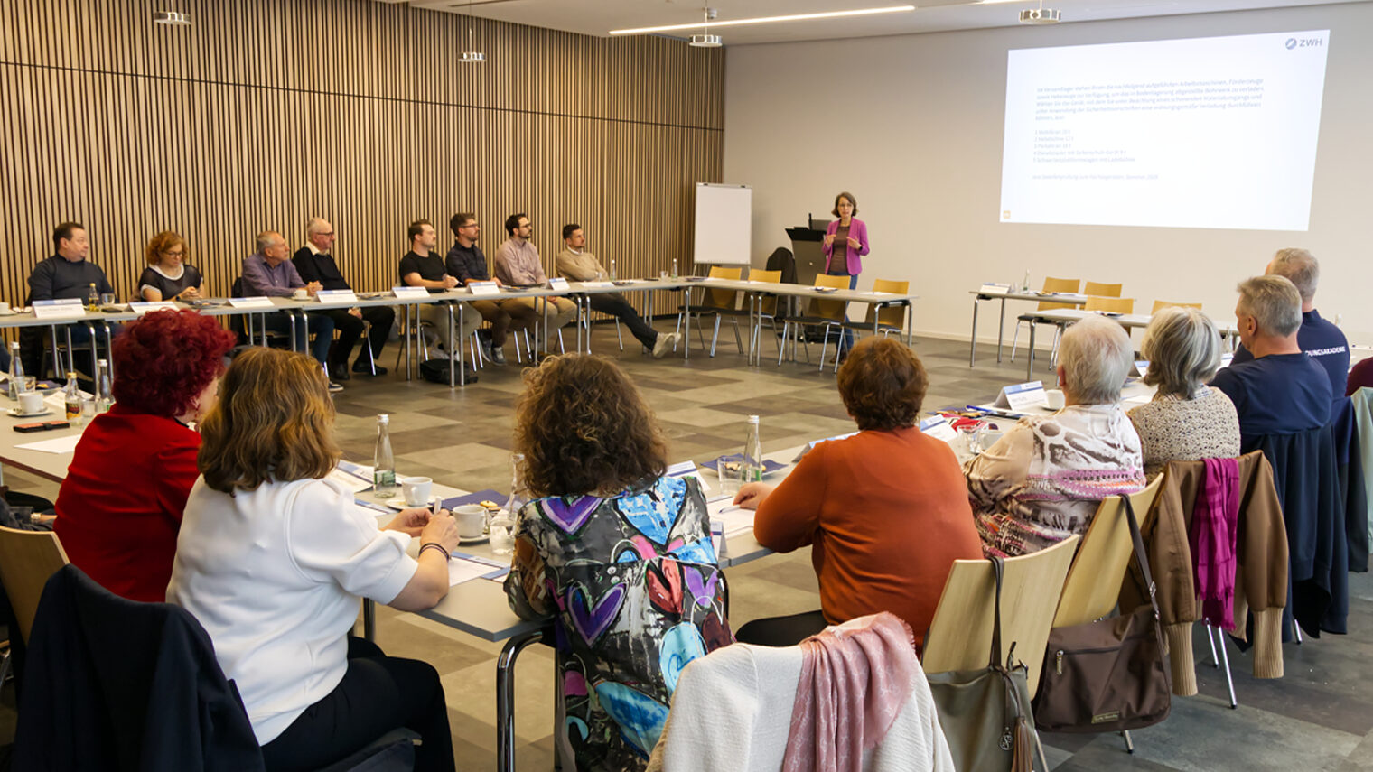 Prüfer in U-Form sitzend und die Referentin anschauend