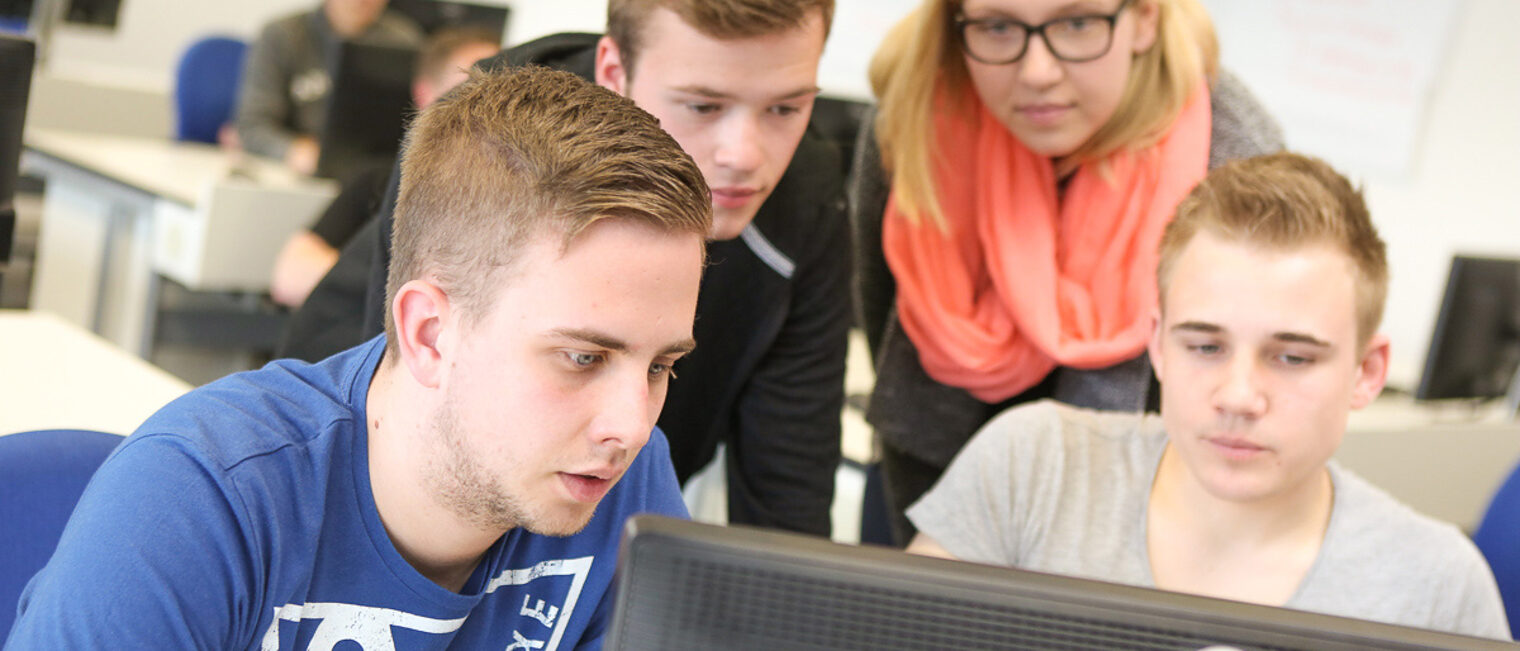eine Gruppe junger Erwachsener sitz vor einem Computer Auszubildende sitzen in einer Arbeizsgruppe vor dem Computer