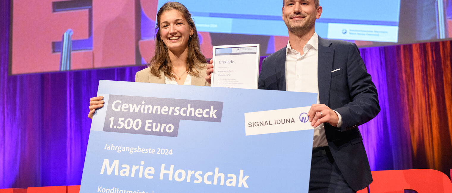 Timo Gindner von Signal Iduna überreicht der Jahrgangsbesten, Konditormeisterin Marie Horschak einen Scheck