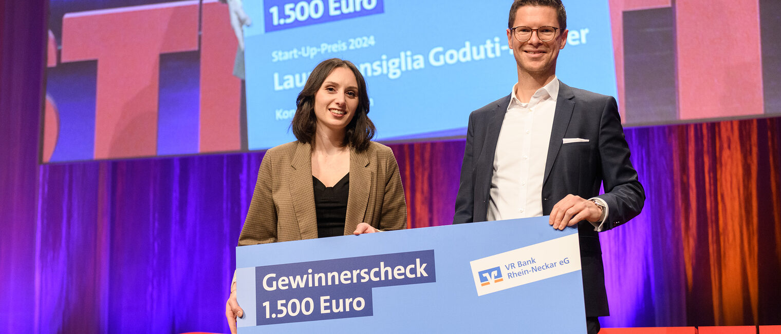 Tobias Pauldrach von VR Bank überreicht der Start-Up Preisträgerin Konditormeisterin Laura Goduti-Meurer einen Scheck
