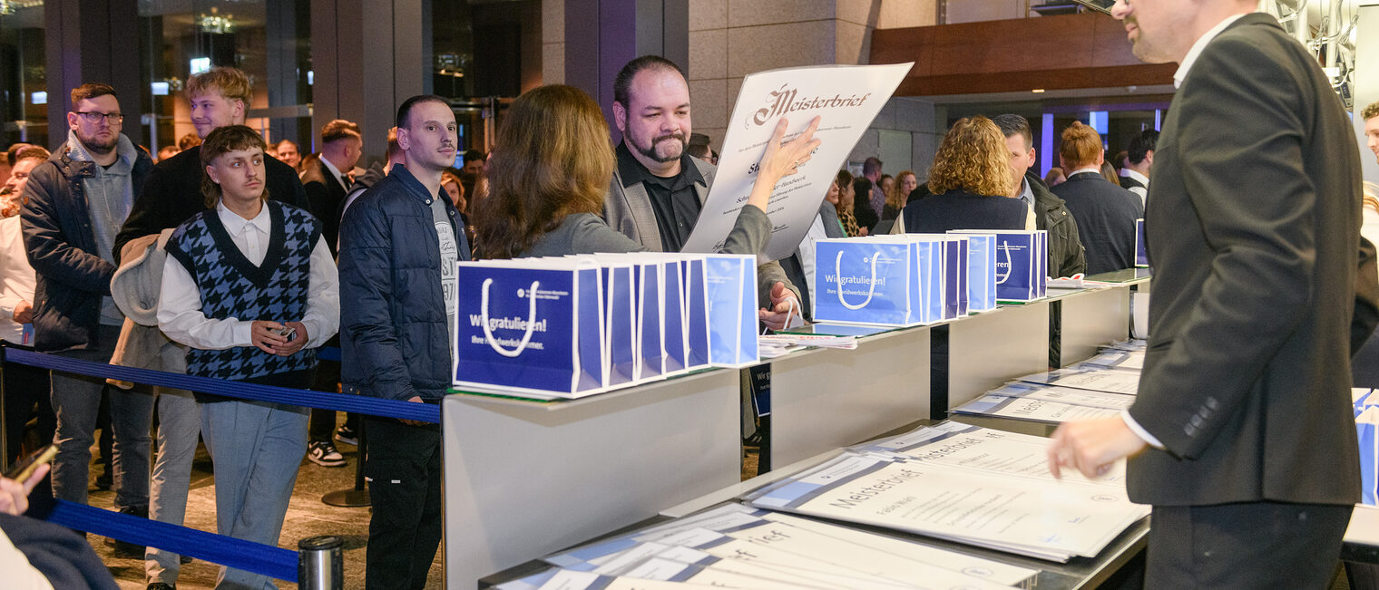Zu sehen ist die Ausgabe der Meisterbriefe an einem Counter im Congresscenter Rosengarten. Die Meisterbriefe werden dort berreicht. 
