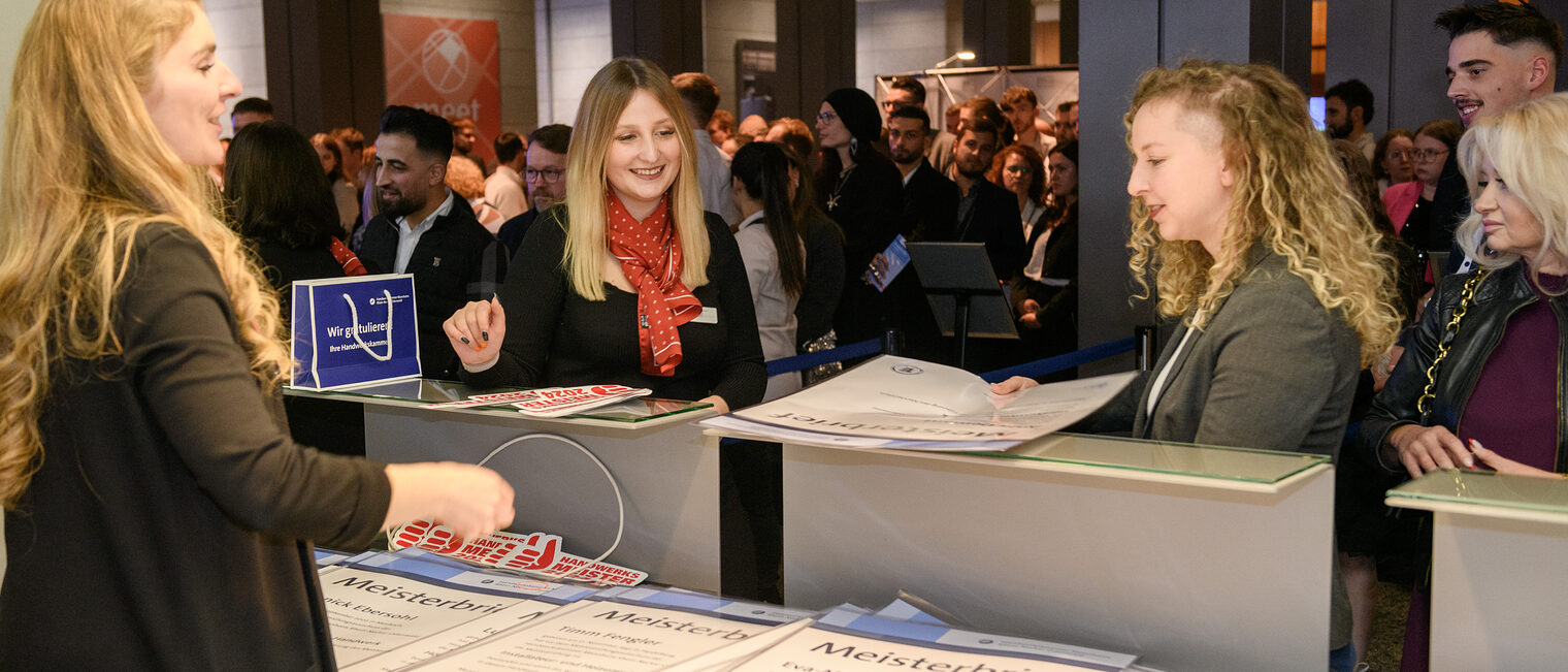 Zu sehen ist die Ausgabe der Meisterbriefe an einem Counter im Congresscenter Rosengarten. Die Meisterbriefe werden dort berreicht. 