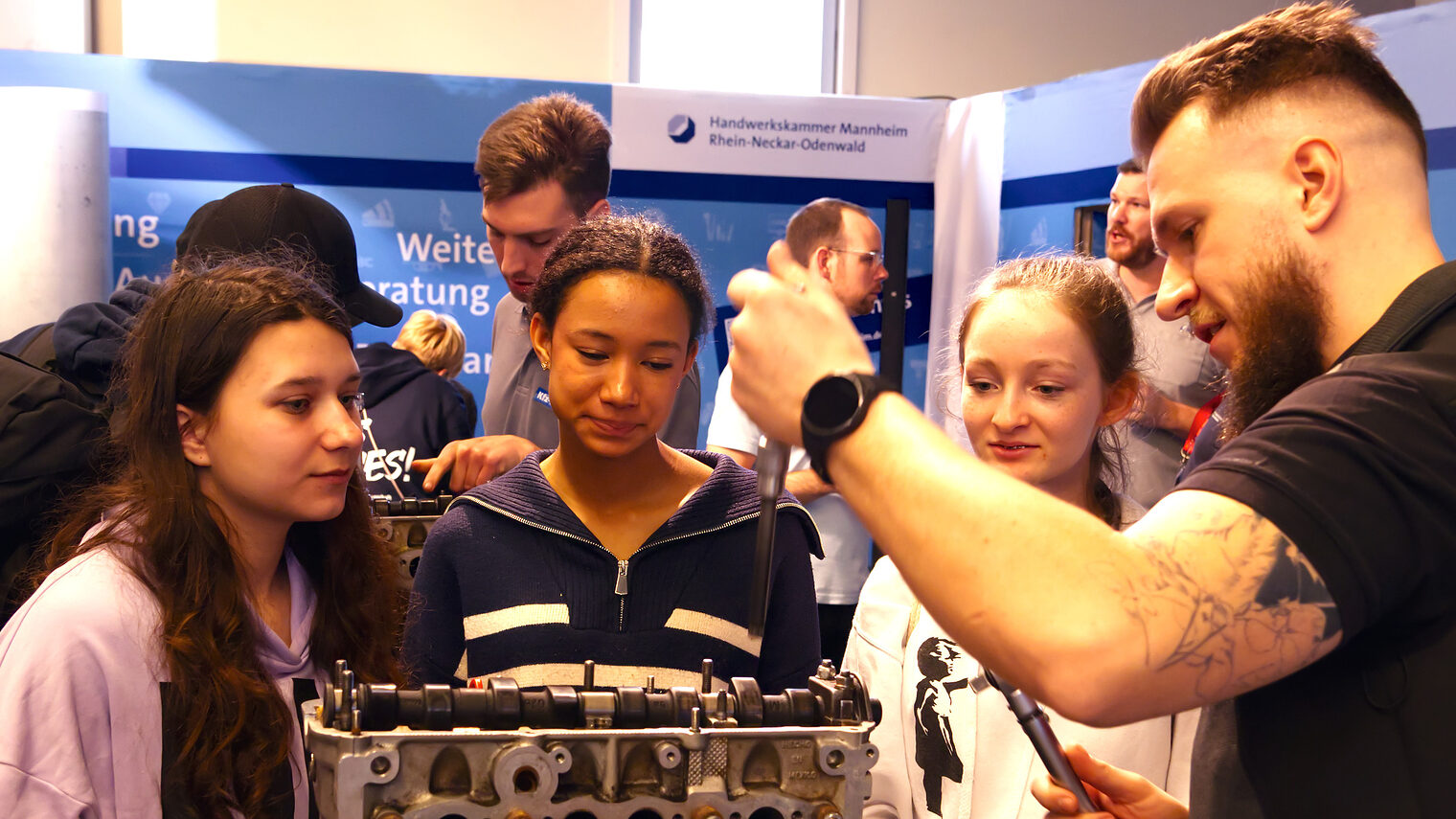 Drei junge Mädchen zeigen sich am Stand der Handwerkskammer bei einer Vorführung interessiert. 