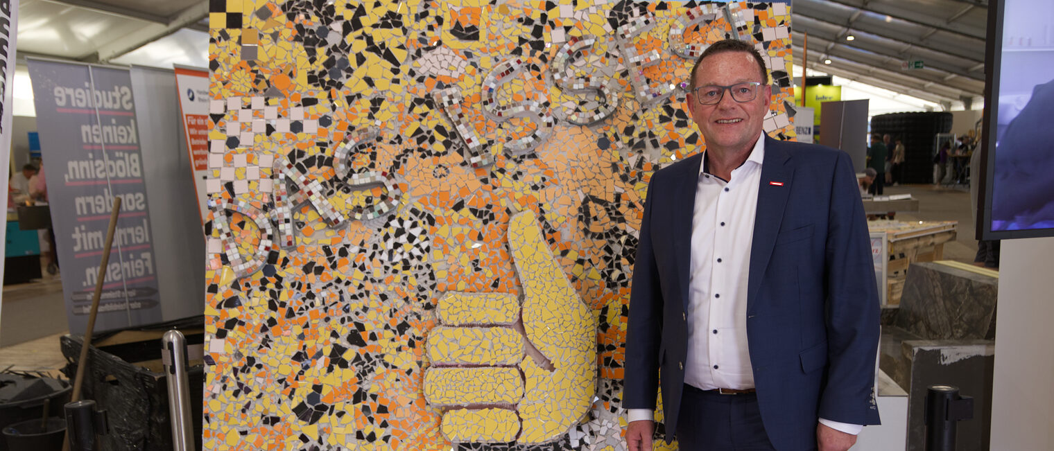 Das Handwerk zieht eine positive Maimarkt-Bilanz: Alle Erwartungen mehr als erfüllt Präsident der Handwerkskammer Mannheim Klaus Hofmann vor buntem Mosaik mit Daumen-hoch-Motiv und dem Schriftzug Das Handwerk