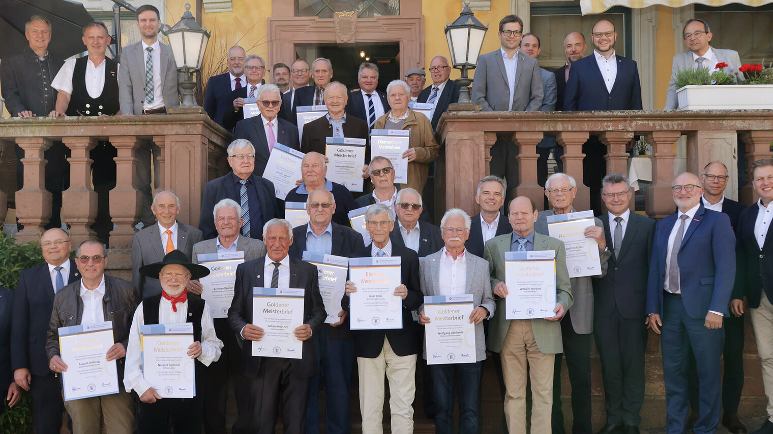 Ein Gruppenfoto von mehreren Handwerksmeistern, die eine Urkunde von der Handwerkskammer erhalten.