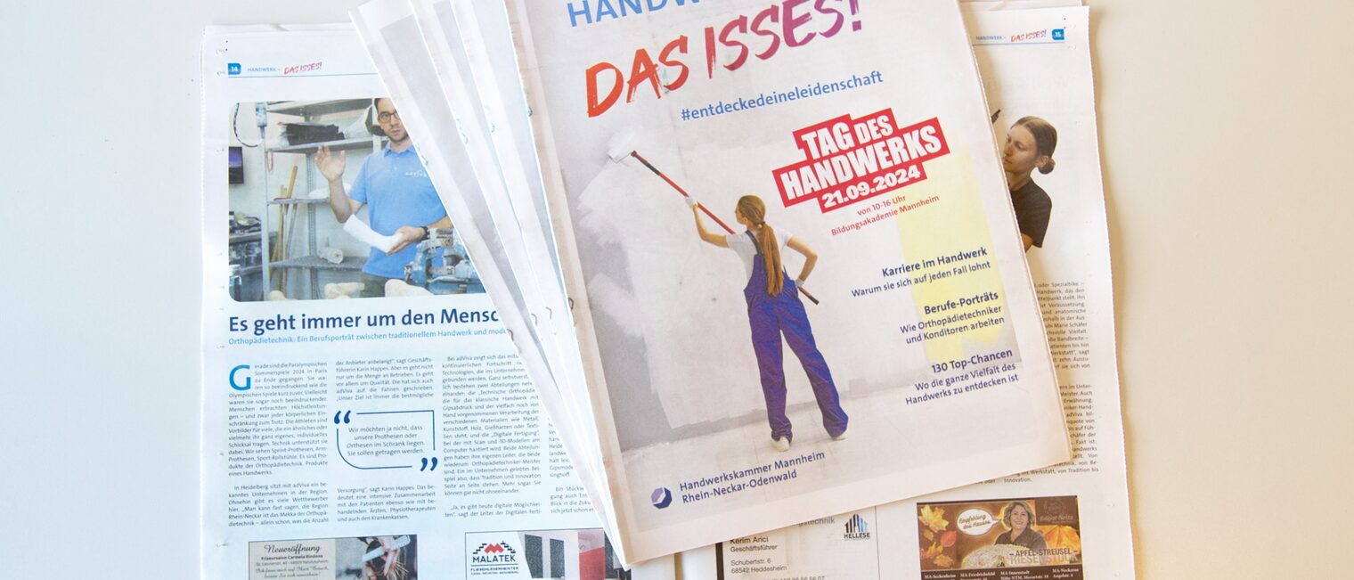 Blick auf aufgeschlagene Zeitung mit Bildern und Texten, darauf liegen aufgefächert weitere Zeitungen mit dem Titel "Handwerk - Das isses!"