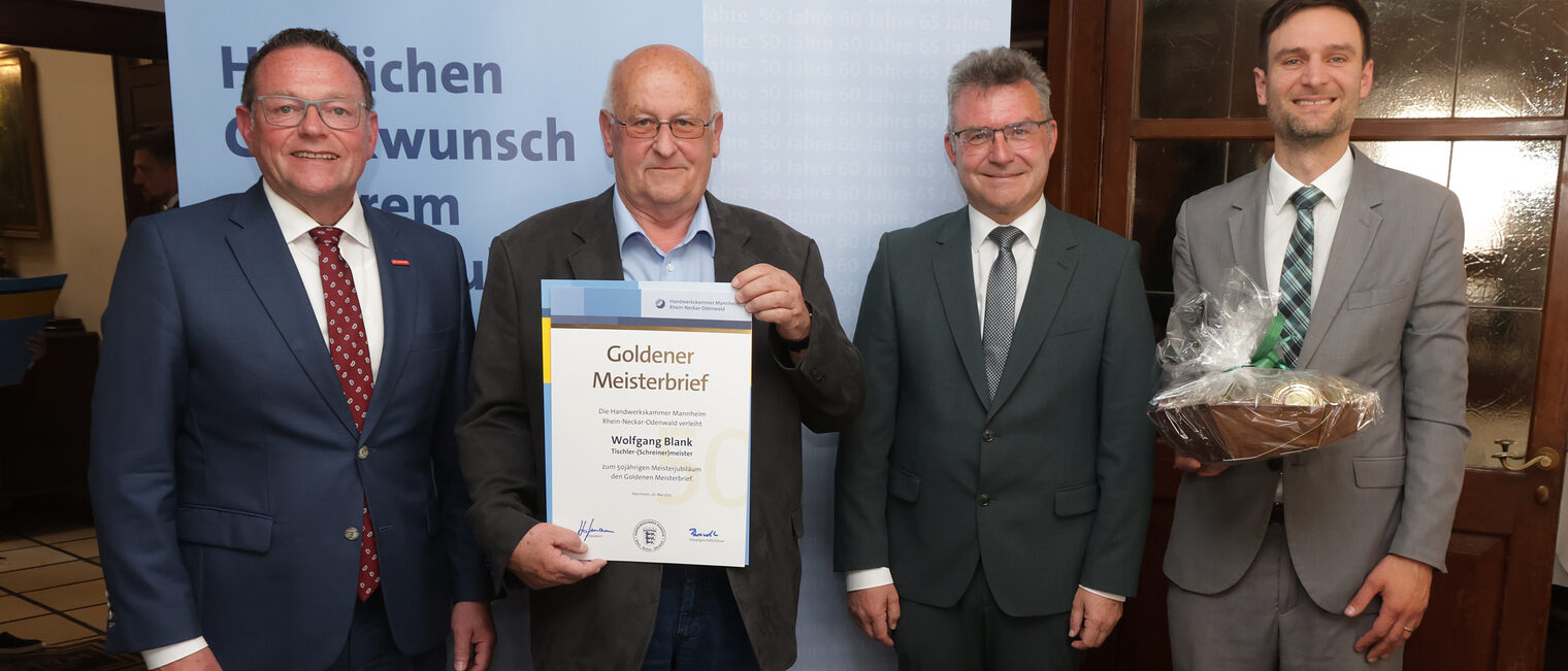 Überreichung der Urkunde zum Meisterjubiläum durch Herrn Klaus Hofmann, der Jubilar hält die Urkunde vor sich.