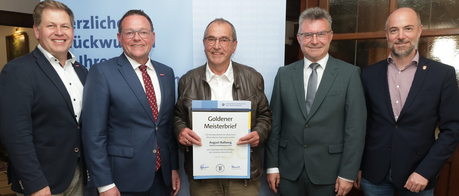 Überreichung der Urkunde zum Meisterjubiläum durch Herrn Klaus Hofmann, der Jubilar hält die Urkunde vor sich.