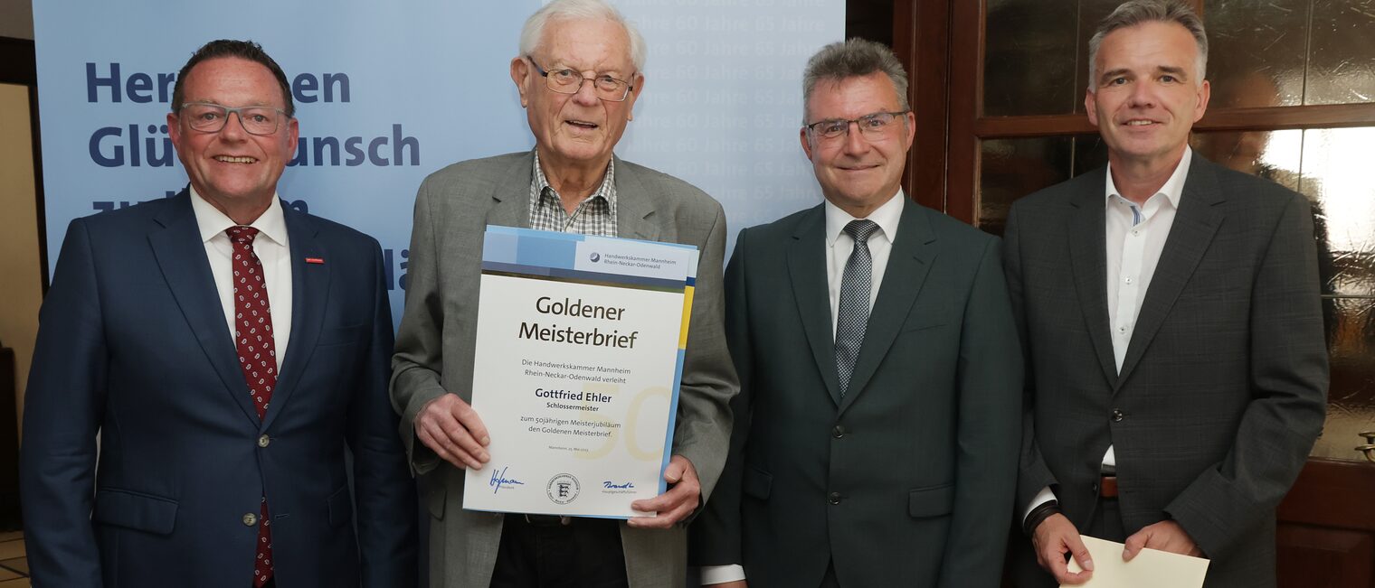 Überreichung der Urkunde zum Meisterjubiläum durch Herrn Klaus Hofmann, der Jubilar hält die Urkunde vor sich.