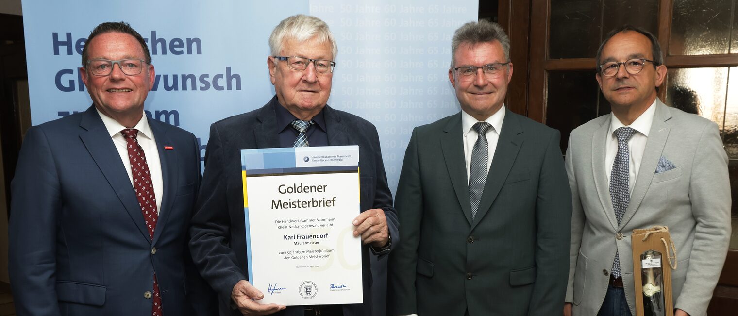 Überreichung der Urkunde zum Meisterjubiläum durch Herrn Klaus Hofmann, der Jubilar hält die Urkunde vor sich.