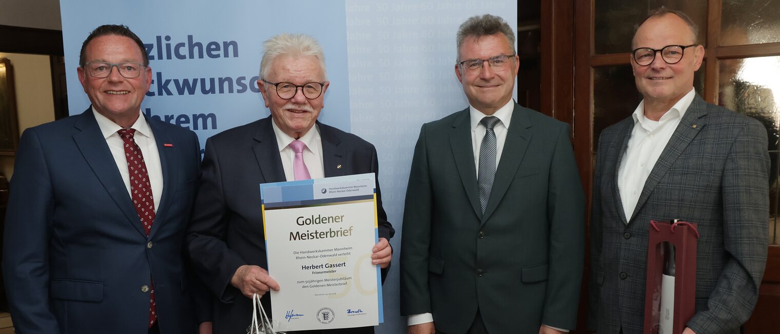Überreichung der Urkunde zum Meisterjubiläum durch Herrn Klaus Hofmann, der Jubilar hält die Urkunde vor sich.