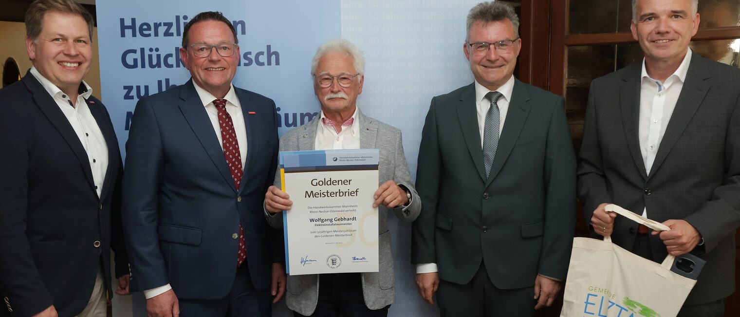 Überreichung der Urkunde zum Meisterjubiläum durch Herrn Klaus Hofmann, der Jubilar hält die Urkunde vor sich.