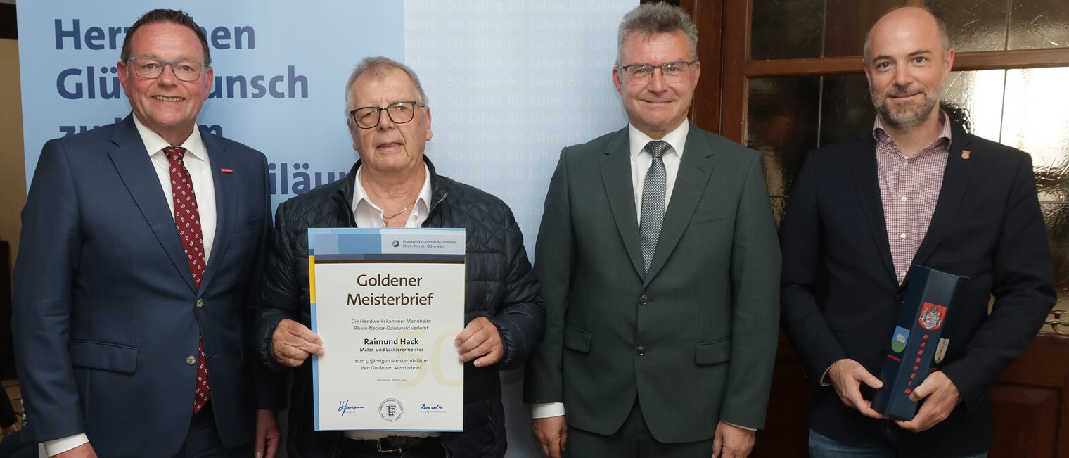 Überreichung der Urkunde zum Meisterjubiläum durch Herrn Klaus Hofmann, der Jubilar hält die Urkunde vor sich.