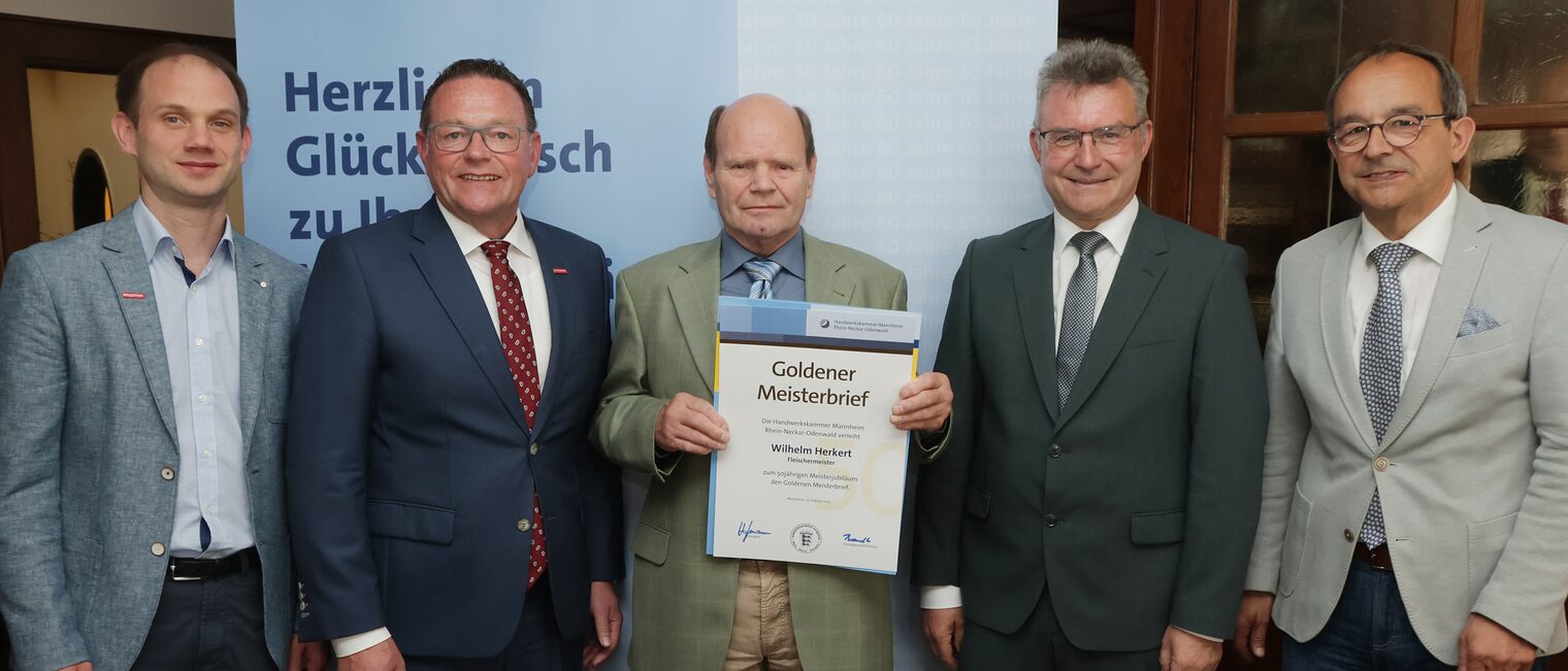 Überreichung der Urkunde zum Meisterjubiläum durch Herrn Klaus Hofmann, der Jubilar hält die Urkunde vor sich.