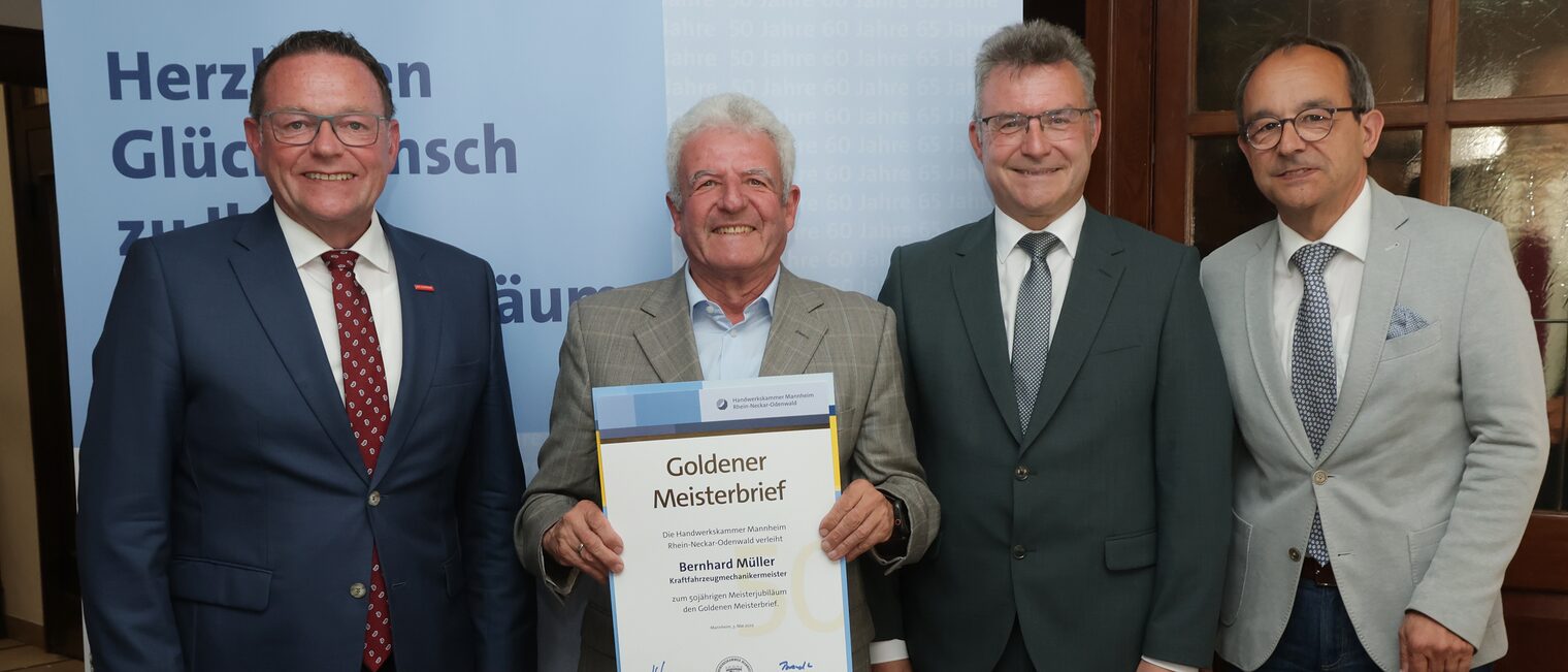 Überreichung der Urkunde zum Meisterjubiläum durch Herrn Klaus Hofmann, der Jubilar hält die Urkunde vor sich.