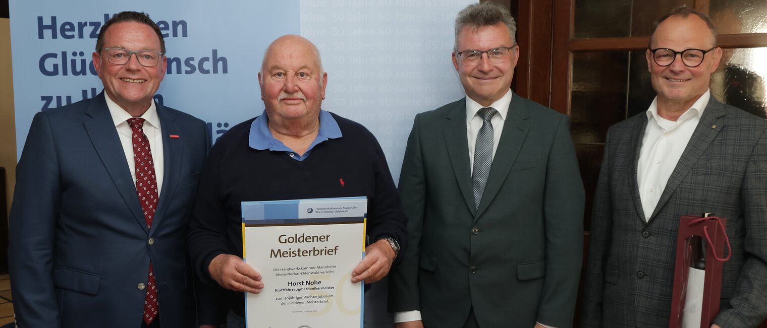 Überreichung der Urkunde zum Meisterjubiläum durch Herrn Klaus Hofmann, der Jubilar hält die Urkunde vor sich.