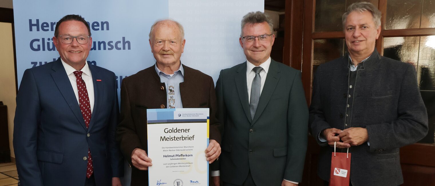 Überreichung der Urkunde zum Meisterjubiläum durch Herrn Klaus Hofmann, der Jubilar hält die Urkunde vor sich.