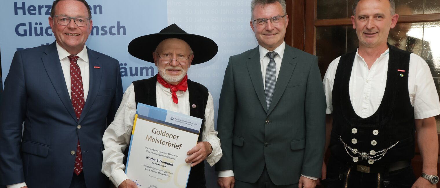 Überreichung der Urkunde zum Meisterjubiläum durch Herrn Klaus Hofmann, der Jubilar hält die Urkunde vor sich.