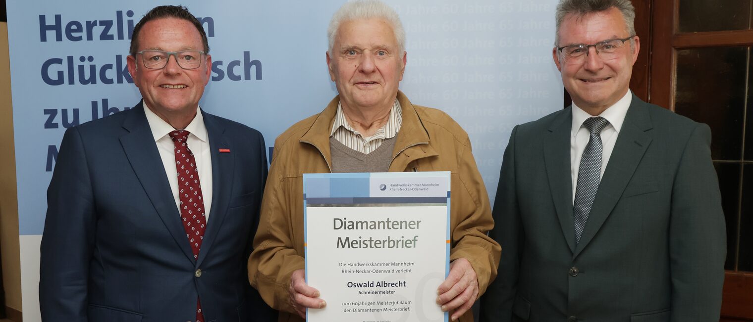 Überreichung der Urkunde zum Meisterjubiläum durch Herrn Klaus Hofmann, der Jubilar hält die Urkunde vor sich.