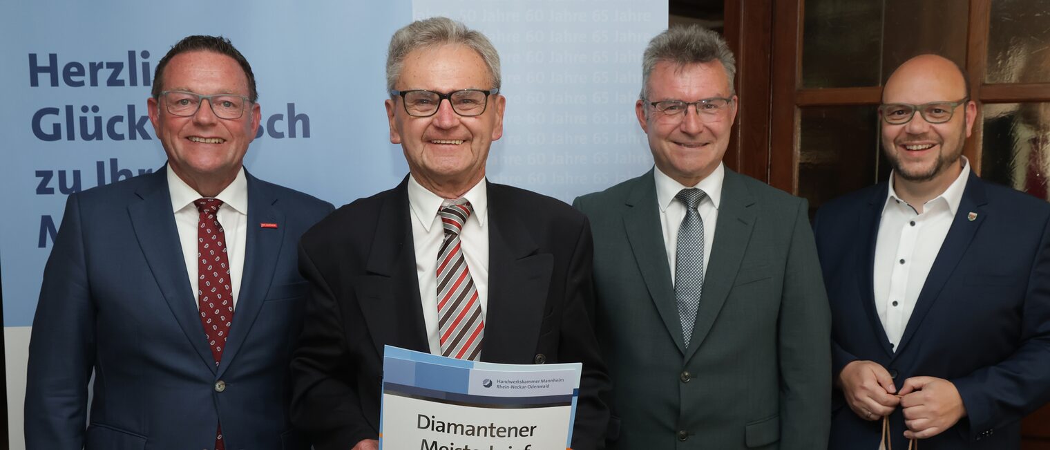 Überreichung der Urkunde zum Meisterjubiläum durch Herrn Klaus Hofmann, der Jubilar hält die Urkunde vor sich.