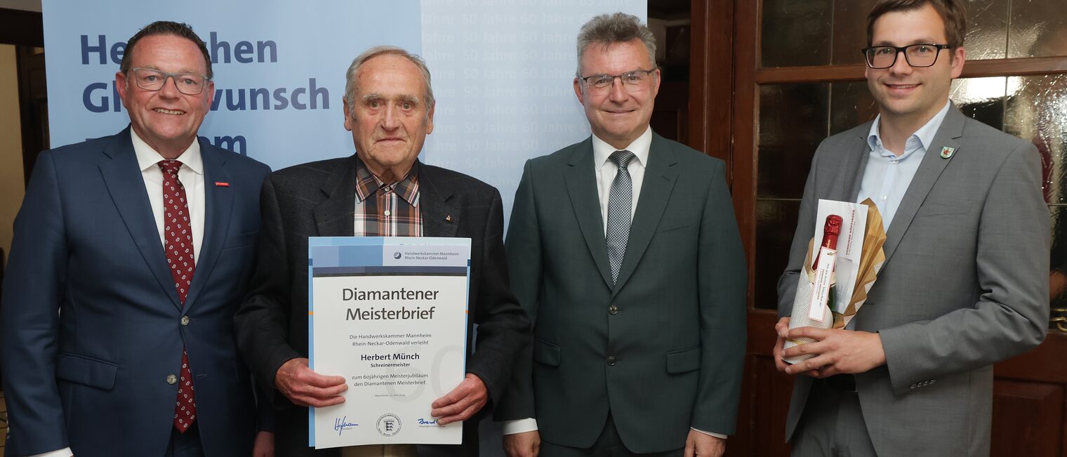 Überreichung der Urkunde zum Meisterjubiläum durch Herrn Klaus Hofmann, der Jubilar hält die Urkunde vor sich.