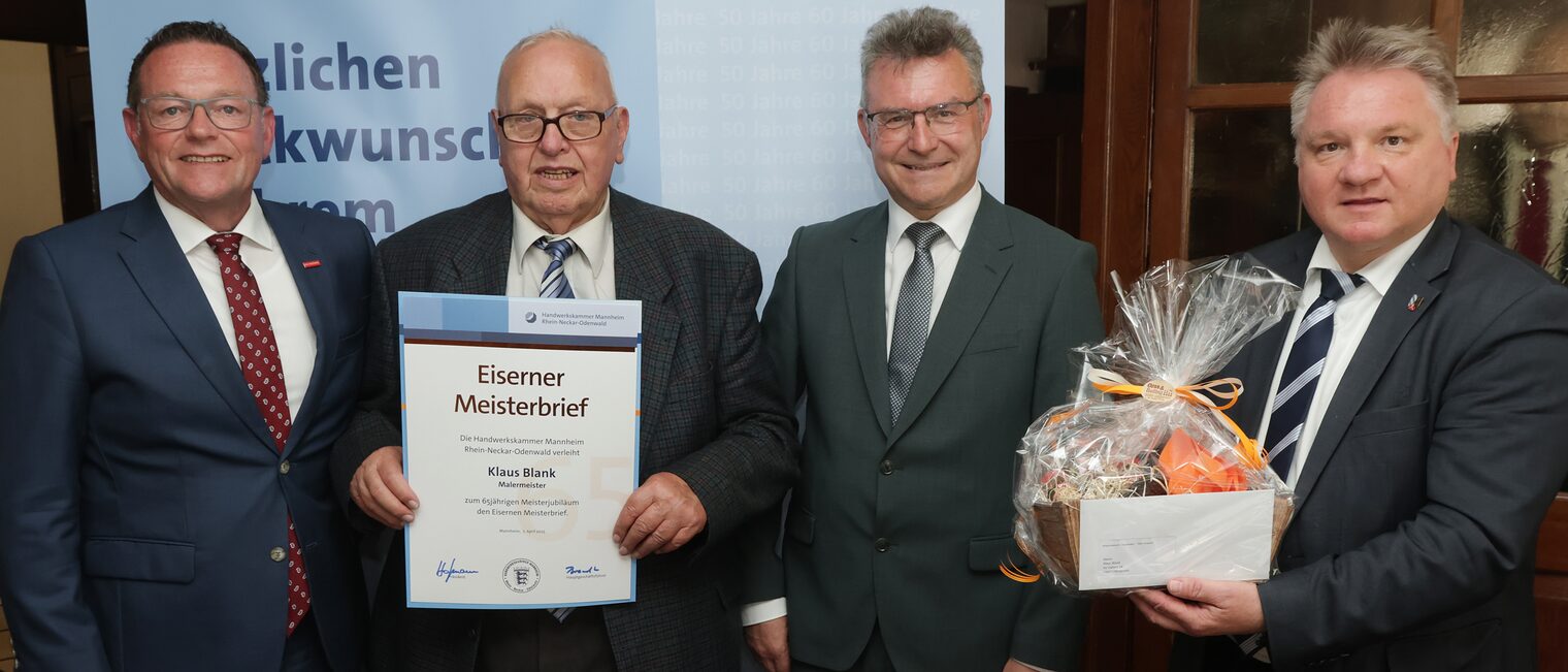 Überreichung der Urkunde zum Meisterjubiläum durch Herrn Klaus Hofmann, der Jubilar hält die Urkunde vor sich.